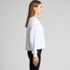 Person in a white long-sleeve shirt and black pants standing in profile against a gray background.