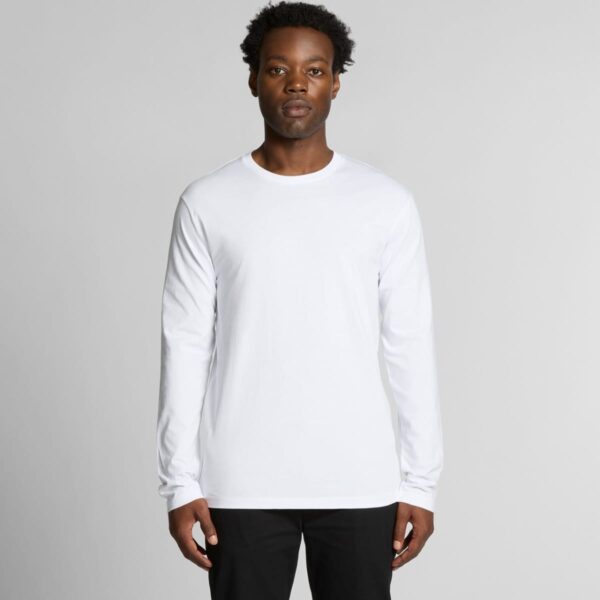 Person wearing a plain white long-sleeve shirt and black pants against a gray background.