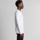 Person in a white long-sleeve shirt stands in profile against a plain background.