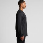 Man in a black long-sleeve shirt stands in profile against a gray background.