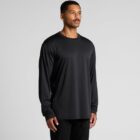 Man in a black long-sleeve shirt and pants looking to the side against a plain background.