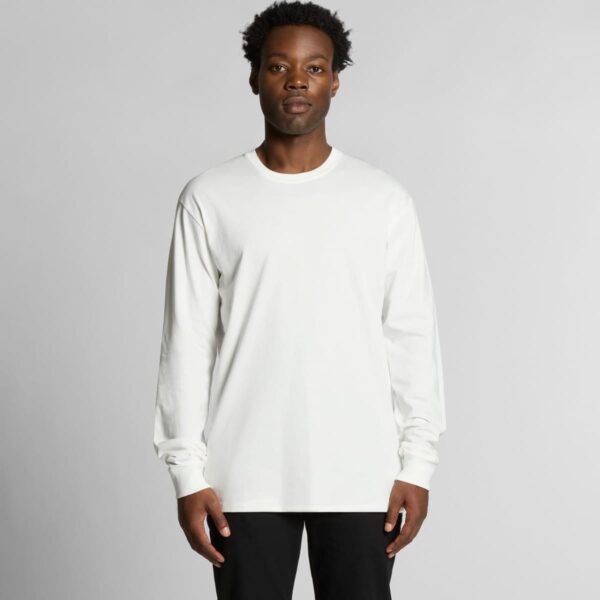 Person in a long-sleeve white shirt and black pants against a neutral background.