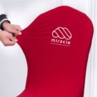 Red chair cover being stretched; miracle smart business solutions logo visible.