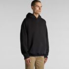 Person wearing a black hoodie and beige pants, standing against a plain background.