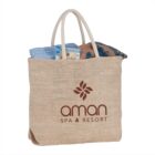 Beige tote bag with aman SPA & RESORT logo, holding towels and bottles.