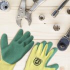 Work gloves and various tools on a wooden surface.