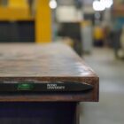 Bubble level on a metal surface in an industrial setting, showing a Bond University logo.