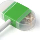 Green pencil sharpener with shavings inside, attached to a white pencil on a white background.