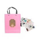 A pink gift bag with a bear design and Thank you text, next to a variety of sticker sheets.