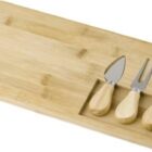 Wooden cheese board with three cheese knives in a cutout section.