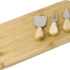Wooden cheese board with three small cheese knives placed on top.