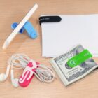 Phone stand, cable organizer, money clip, and paper clip on a wooden surface.