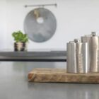 Two metal flasks on a wooden board in a modern kitchen setting.