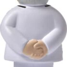 Toy figure in a white suit standing with hands clasped behind its back, facing away.