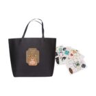 Black tote bag with bear design, accompanied by assorted decorative stickers.