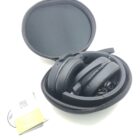 Black headphones folded in a round zippered case with a small booklet beside it.