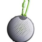 Round portable speaker with green carabiner attached.