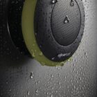 Waterproof shower speaker with droplets on a dark surface.