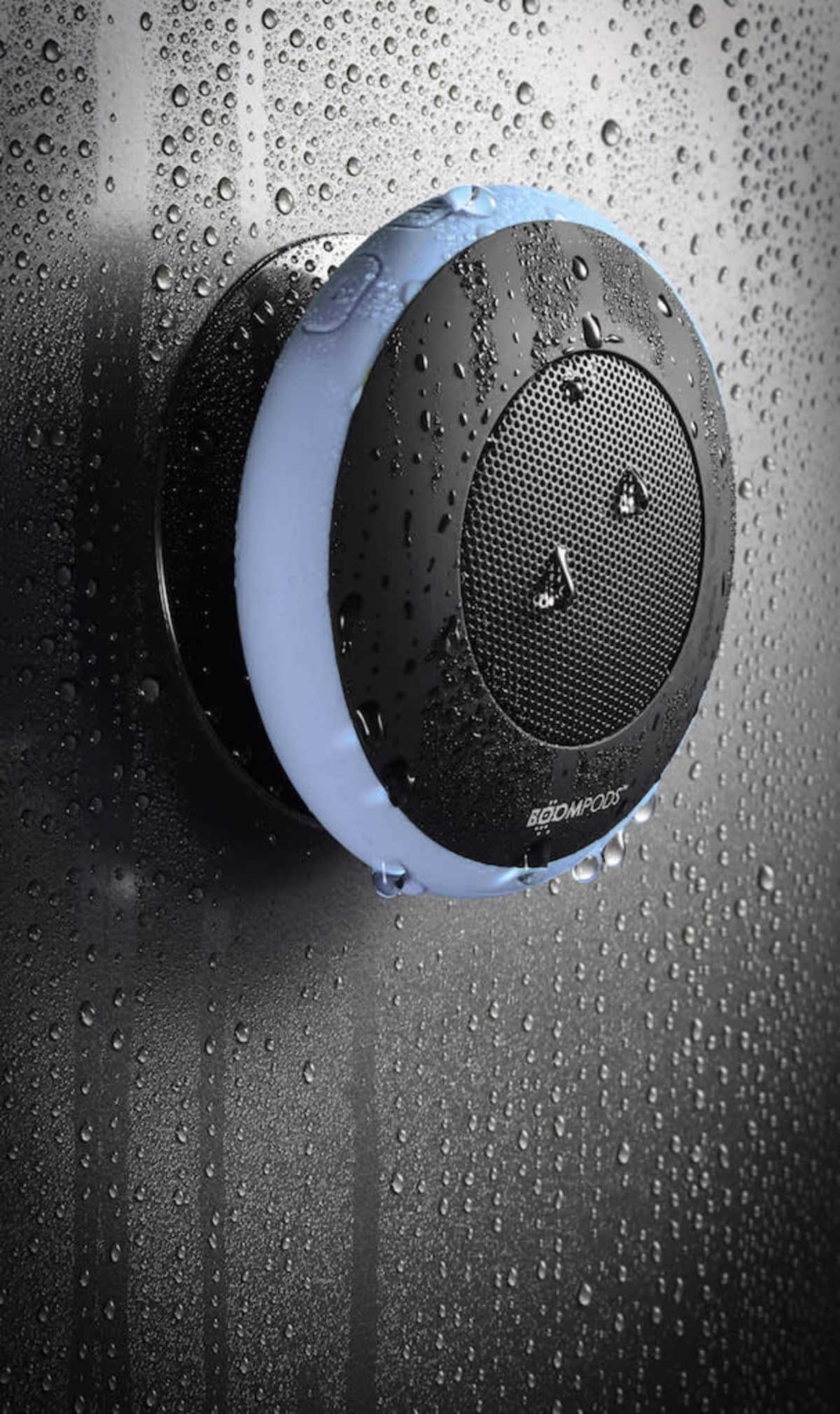 Black waterproof speaker with water droplets on a wet surface.