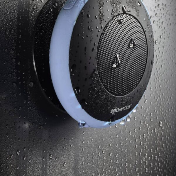 Waterproof black speaker attached to wet glass in a shower environment.
