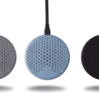 Three round, perforated wireless chargers in gray, blue, and black, floating above shadows.