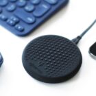 Black wireless charger with textured surface next to a mouse and keyboard.