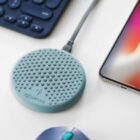 Blue wireless charging pad with a connected cable, beside a smartphone and keyboard.