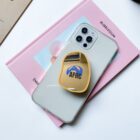 Smartphone with yellow AFRC grip on two pastel books.