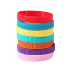 Stack of colorful silicone wristbands with various texts.