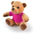 A brown teddy bear wearing a bright pink shirt, sitting upright on a white background.