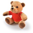 Plush brown teddy bear wearing a red shirt, sitting on a white background.