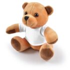 Brown teddy bear wearing a plain white T-shirt, sitting on a white background.
