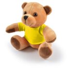 A brown plush teddy bear wearing a bright yellow shirt, sitting upright.