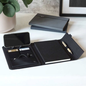 Open organizer with a phone, cards, notebook, and pen on a white desk—a timeless marketing touch. Closed promotional diary in the background adds an air of professionalism.