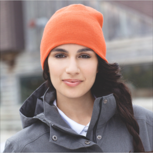Person wearing an orange beanie and gray jacket, standing outdoors with a slight smile—a perfect addition to Shea’s Top 5 Autumn Merch favorites.