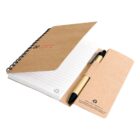 A spiral-bound notebook with a brown recycled paper cover is open to reveal lined pages. A pen with a brown barrel sits in a matching recycled paper holder beside the notebook. Recycle symbols and text are on both cover and holder.