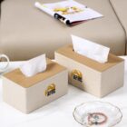 Two tissue boxes on a table, with a magazine and sofa in the background.