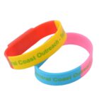 Two colorful wristbands with green text, one red and yellow, one pink and blue.