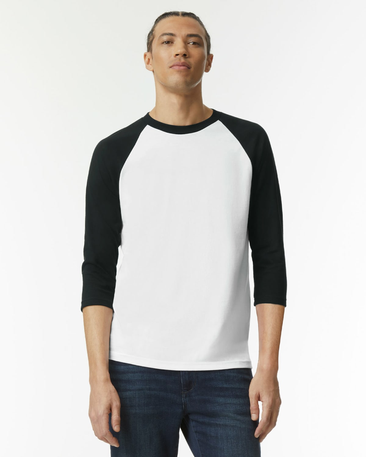 Person wearing a white shirt with black sleeves and blue jeans, standing against a white background.