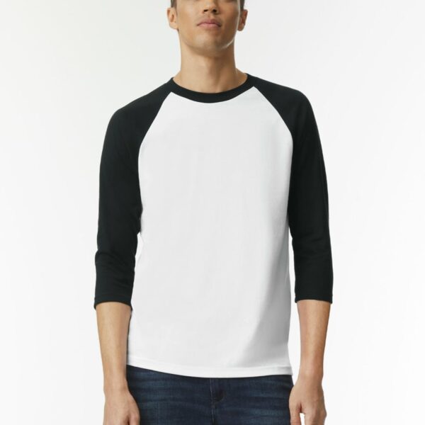 Person wearing a white and black raglan shirt and dark jeans, standing against a plain background.