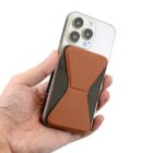 Hand holding a phone with a brown adhesive card holder on the back.