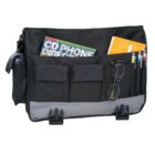 A black and gray messenger bag with several pockets, containing a magazine, a notebook, a pair of eyeglasses, and various colored pens. Two buckle closures are visible at the bottom.