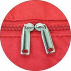Image shows three detailed views of a red bag. Left: sneakers inside an open pocket. Middle: close-up of two metal zippers. Right: a black plastic buckle on an adjustable strap.