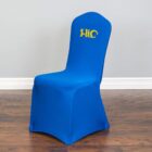 Blue chair with yellow logo on top, over a wooden floor and in front of a gray wall.