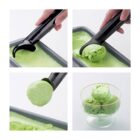 Scooping green ice cream from a tray into a glass dish using a black ice cream scooper.
