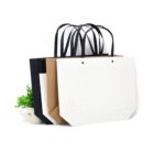 Three shopping bags in black, brown, and white near a small potted plant.
