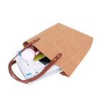A brown tote bag with documents, phone, and a pink container peeking out.