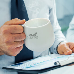 Person holding a steaming mug with a logo, reading a clipboard with charts for products designed for conference promotions.