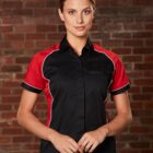 Person in black and red shirt standing against a brick wall.