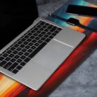 Laptop, smartphone, and smart watch on a colorful desk mat.